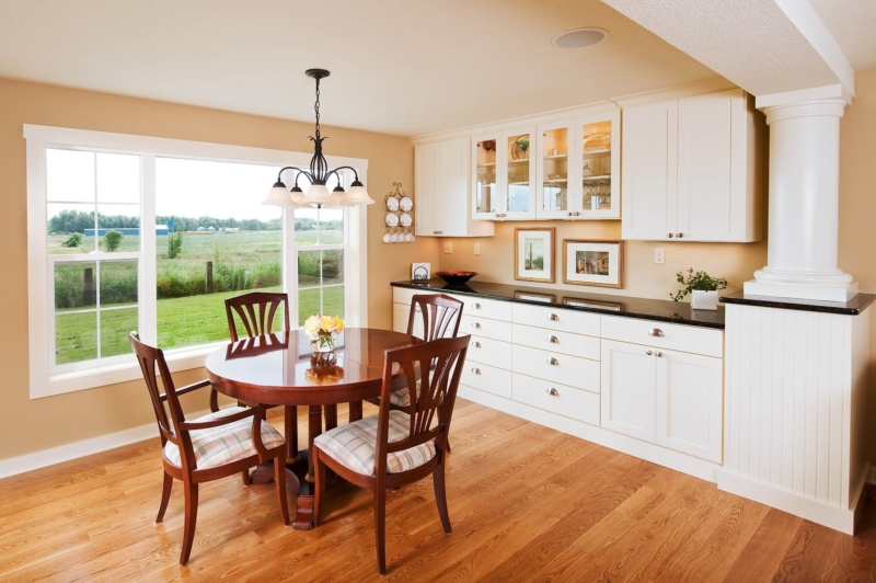 A custom white buffet in the dining room and white columns that support the beam concealed in the ceiling. Bedroom interior with curtains