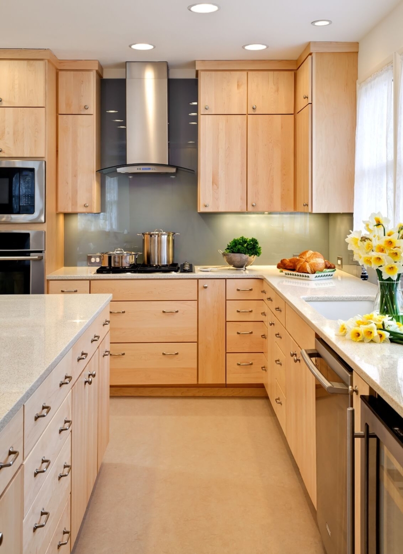 A maple kitchen with a backsplash using architectural glass. Caesarstone countertops, and flat-slab cabinet doors and drawers made of maple Exterior of historic home renovation