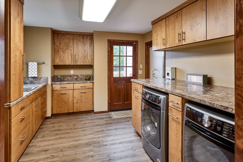 overview of laundry room with dark cabinets and hardwood floors 