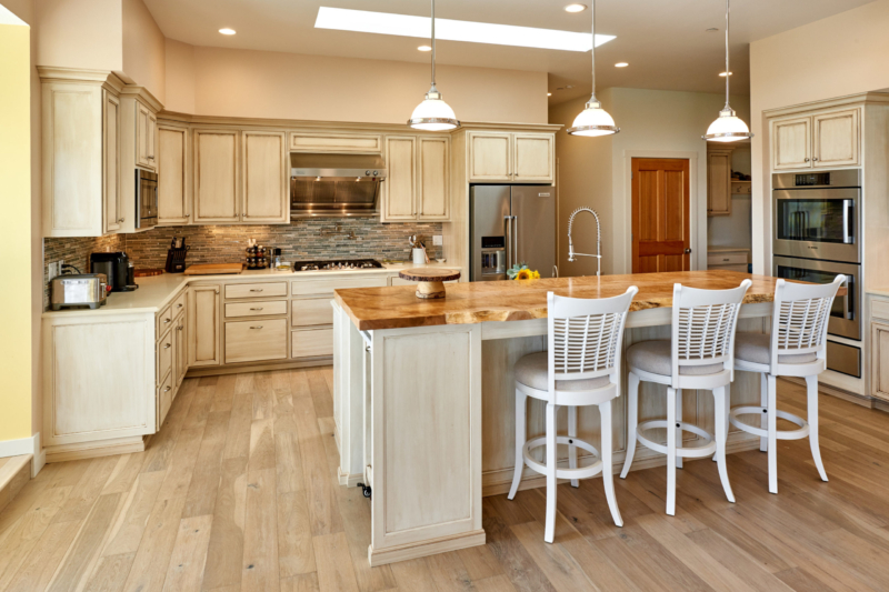 Pendant lights above kitchen island with a perimeter of white glazed cabinets 