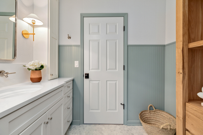 White interior door with blue trim and wainscotting in small master bath