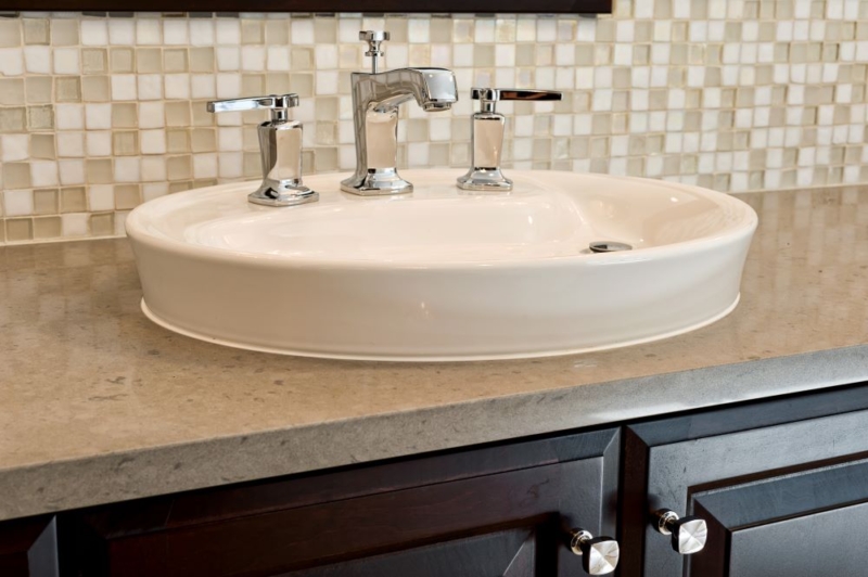 Glass mosaic backsplash tiles harmonize with the quartz counter in this bathroom remodel.