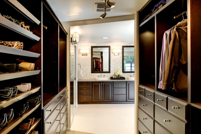 Walk in closet with richly stained cabinetry.