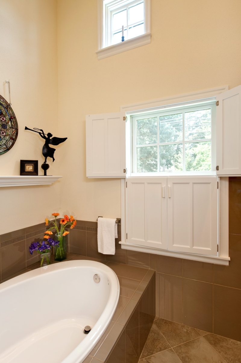 The bathroom features an extra deep soaking tub room. The shuttered window provides charm and privacy. Contemporary bathroom remodel