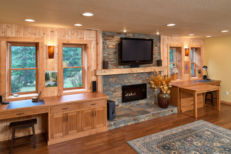 A Heat and Glo gas fireplace in Martini bronze finish, a wall-mounted television above the fireplace, sconces from Besa Lighting in Amber cloud, and bespoke desks on either side of the fireplace. Cape Cod home exterior with landscaping