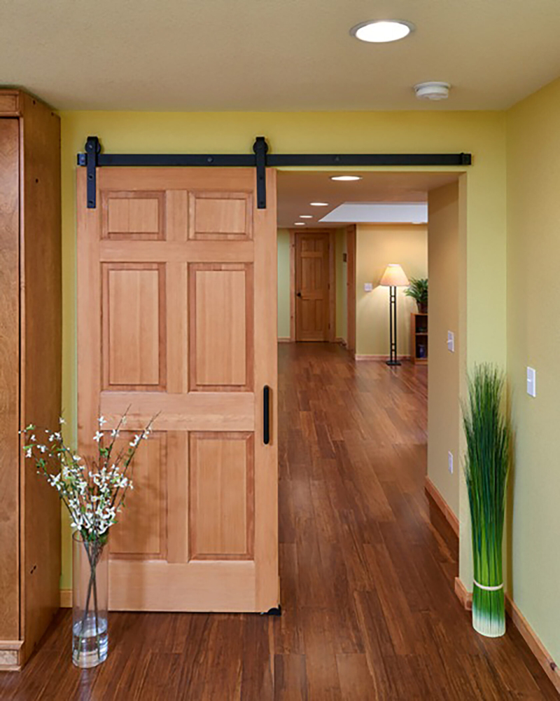 A sliding barn door is hung using classic flat track hardware is from Rustica Hardware. Stained bamboo flooring is from Arcade. Log home basement interior