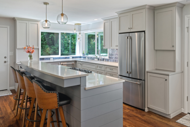 Light grey island with raised eating bar in this kitchen remodel by Powell Construction. Light grey island with raised eating bar.