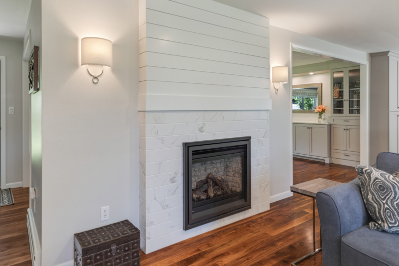 Gas fireplace with white, stone surround and white shiplap above. Gas fireplace with white, stone surround and white shiplap above.