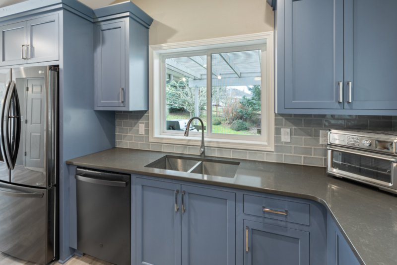 Quartz countertops with brushed nickel fixtures. Window over sink with brushed nickel faucet and dark quartz counter.