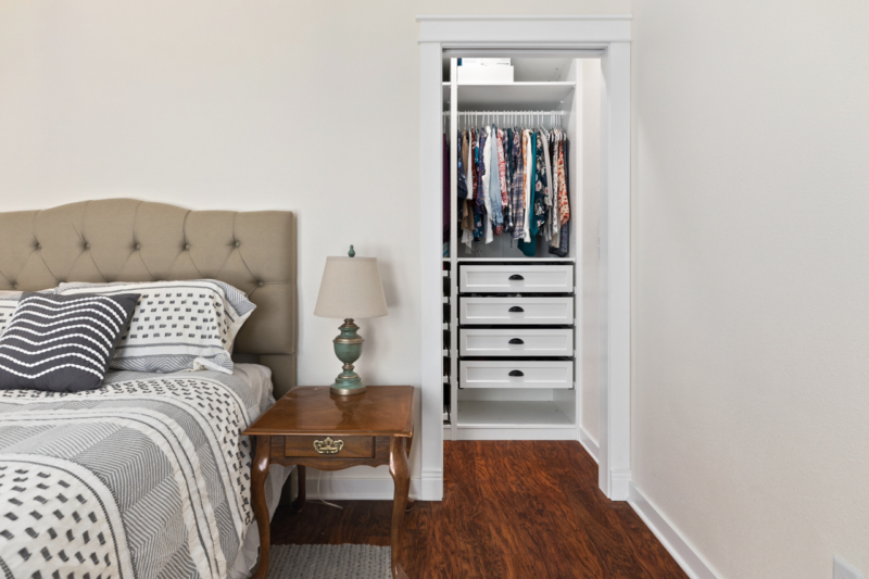 Long walk-through closet with two entry/exit doors in the bedroom by Powell Construction Walk-through closet behind wall in primary bedroom