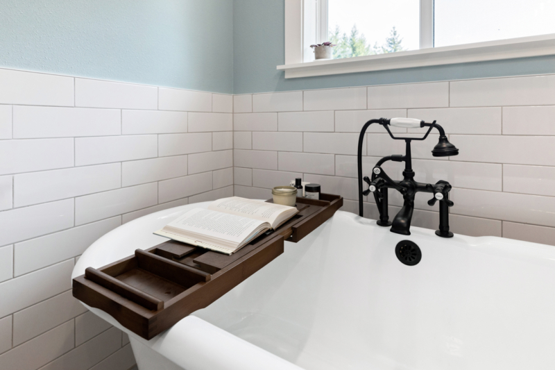 Modern farmhouse bath remodel with freestanding tub Bathtub caddy over free standing tub in farmhouse style addition.