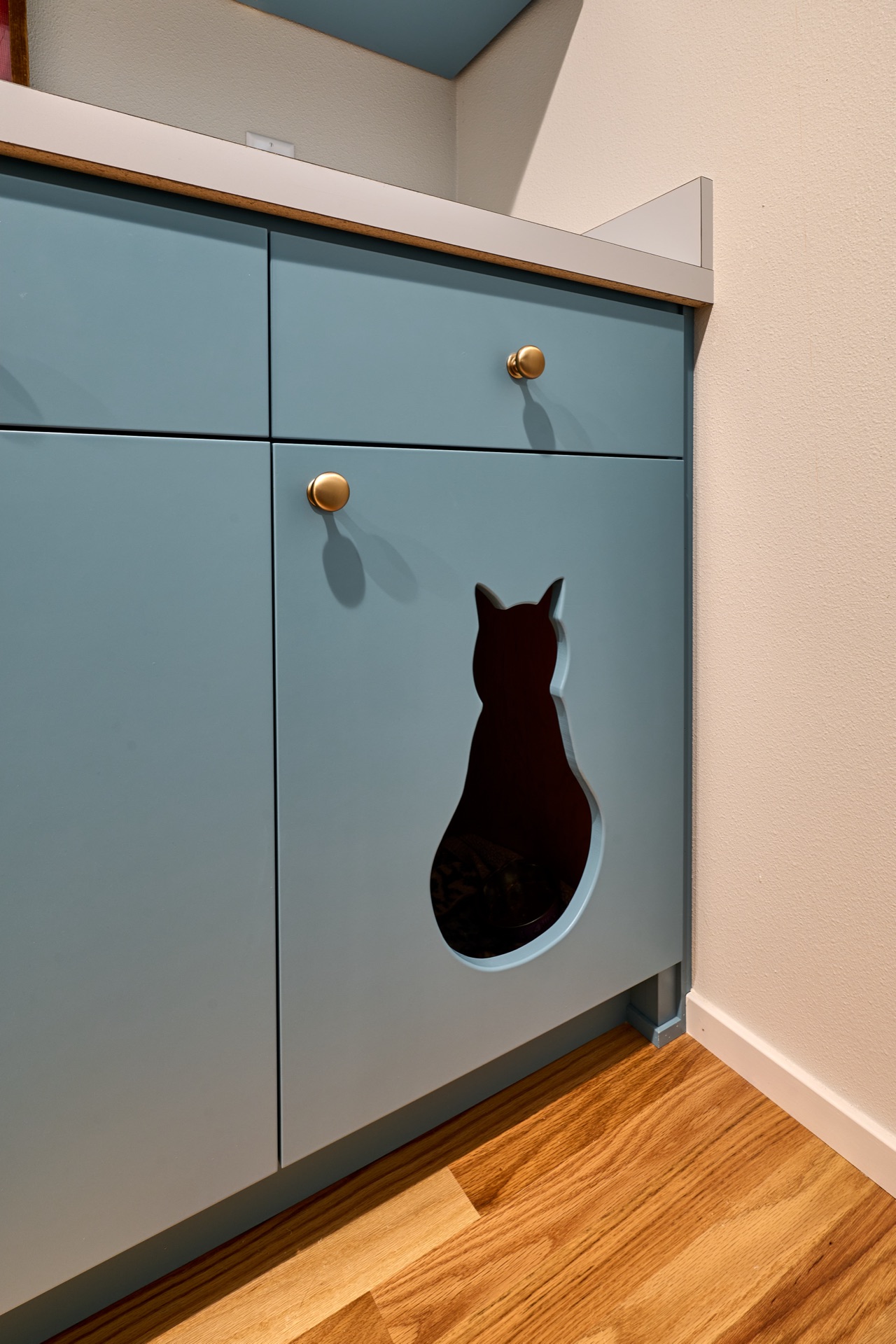 Clever kitty cutout conceals litter in laundry by Powell Construction