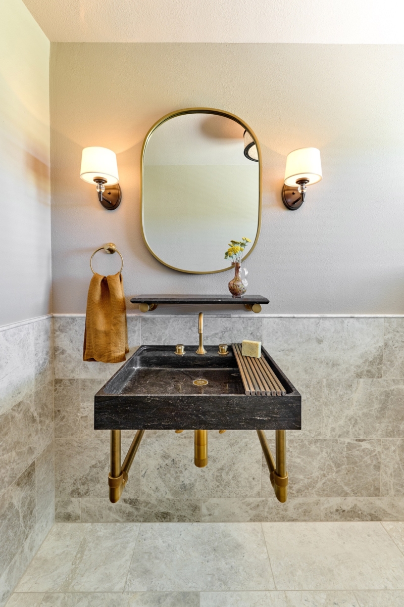 Limestone sink with brushed gold fixtures in powder room by Powell Construction