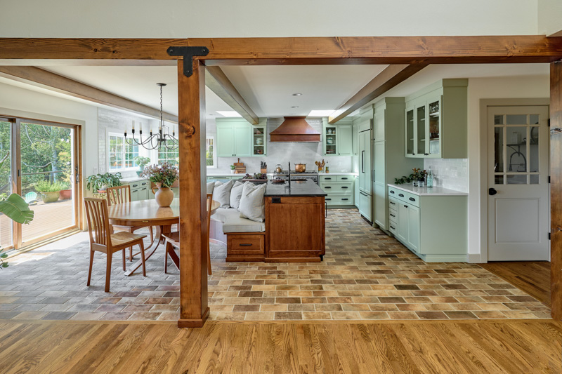 Photo of a New England inspired kitchen remodel by Powell Construction. The brick tile and soft green cabinets are standouts in this bright and airy kitchen.