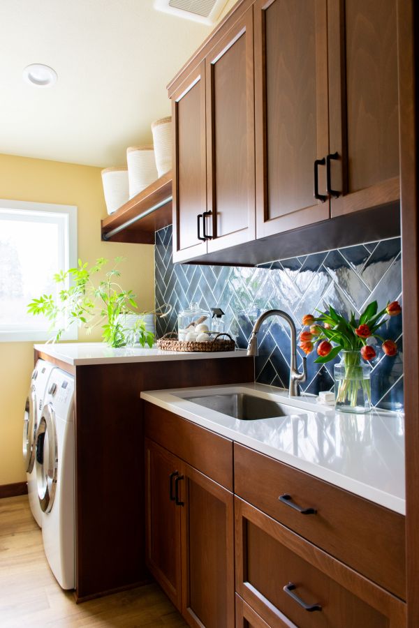 Glossy blue backsplash tile in herringbone pattern in laundry room addition by Powell Construction..