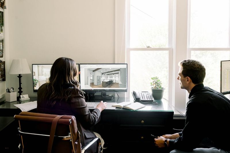 Photo of a Powell Construction designer and Project Coordinator, conferring over a kitchen design plan.
