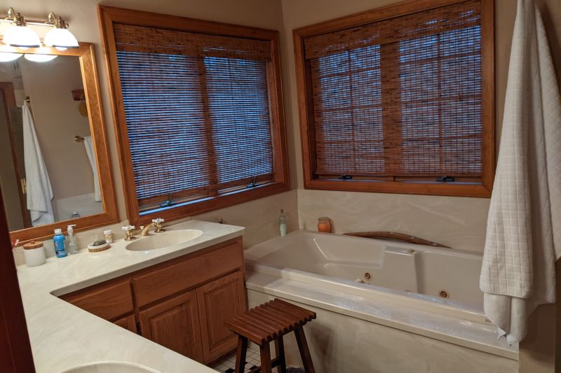 Bathroom with L-shaped vanity, prior to remodel was poorly configured with tired finishes.