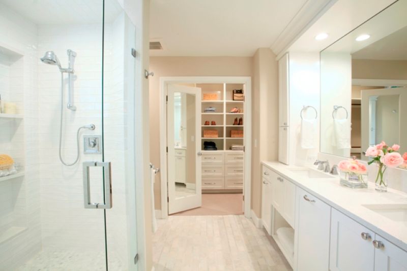 This bright and airy primary bathroom includes a spacious shower, dual vanity and walk-in closet with custom storage. Remodeled by Powell Construction.