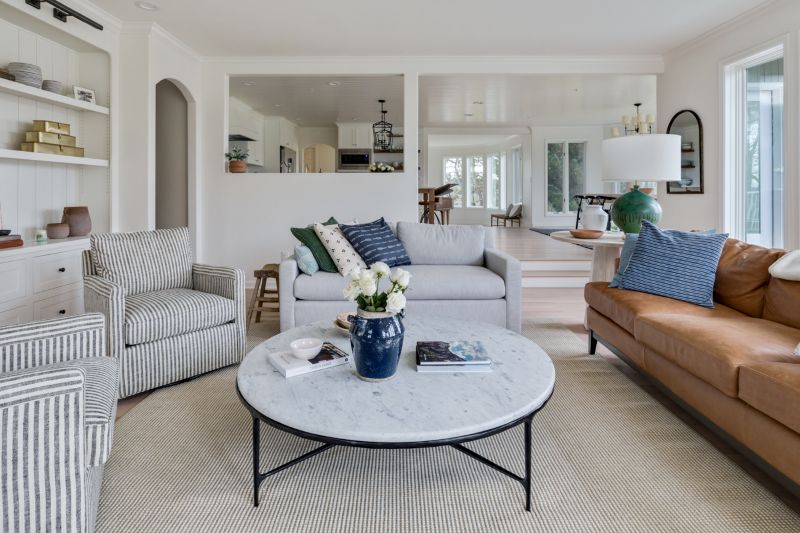 View from a remodeled living room into the newly renovated, white modern farmhouse kitchen. The cohesive look is bright and refreshing.