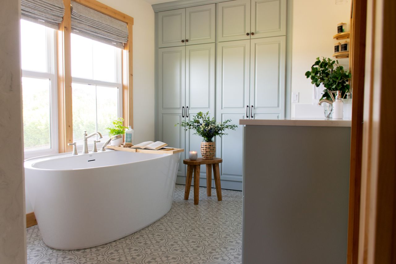 Gorgeous modern farmhouse primary bath remodel with soft green custom cabinetry.