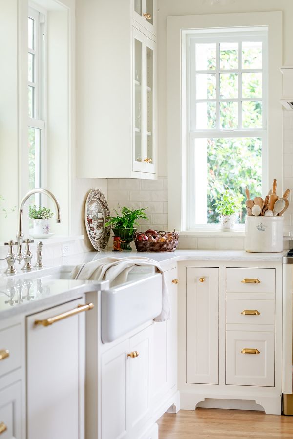 English cottage–style kitchen featuring an apron-front sink paired with an elegant polished nickel bridge faucet.