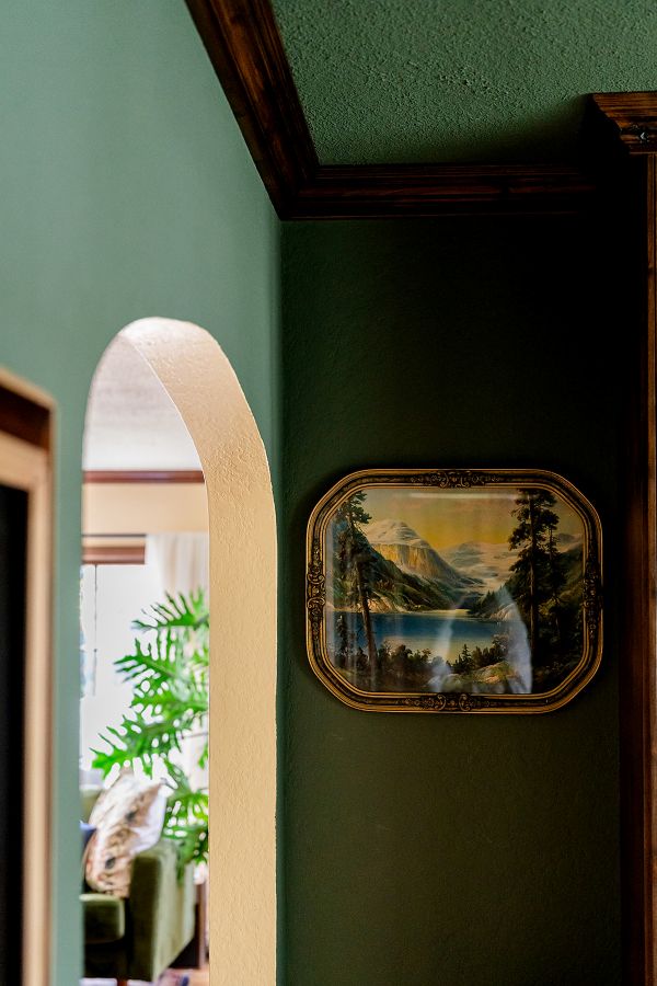 Detailed view of archway connecting English cottage study and living room, with green walls in study and yellow transition in archway leading to living room.