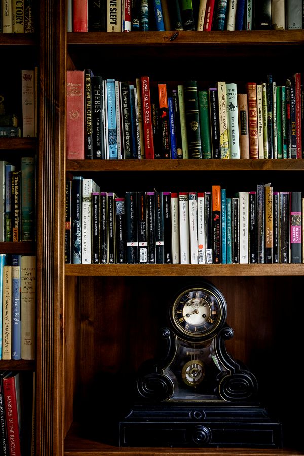 Close-up of custom built-in bookcase in study with mantle clock and rows of books.