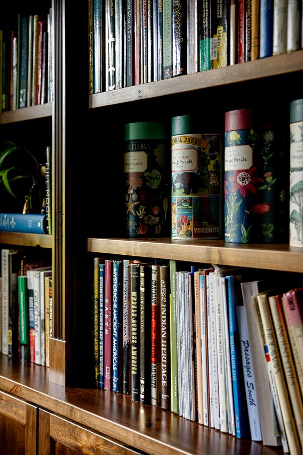 Close up shot of books and puzzles displayed on wood shelves in study.