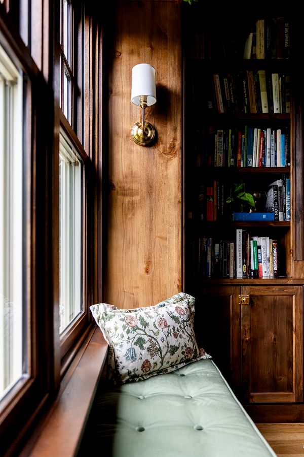 Window seat in study with custom made, velvet cushion and brass wall sconce for reading.