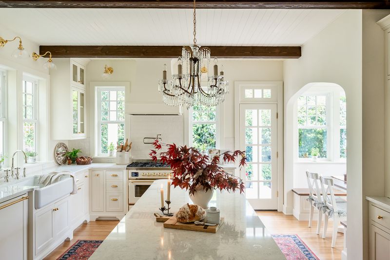 Elegant antique brass chandelier adorned with crystals suspended above a central kitchen island.
