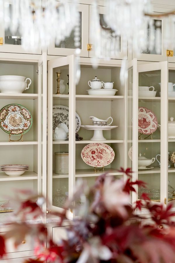 Elegant kitchen hutch with glass doors, featuring a display of seasonal autumn-themed plates and bowls.