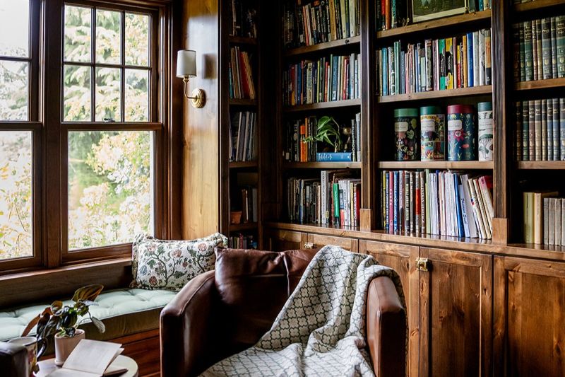 Cozy sitting area in english cottage style study with wood stained built-ins.