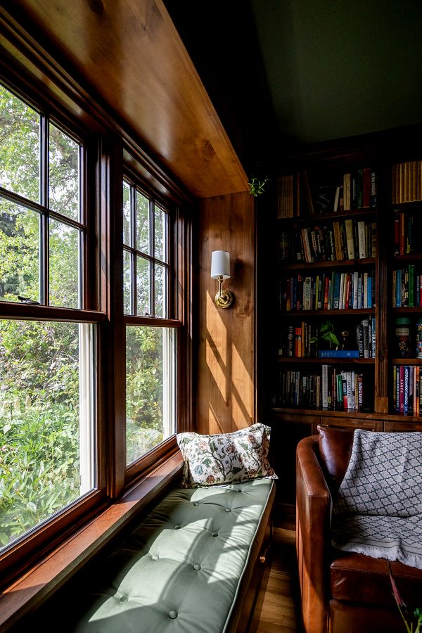 Close-up of study window seat with custom green velvet cushion and wall sconce.