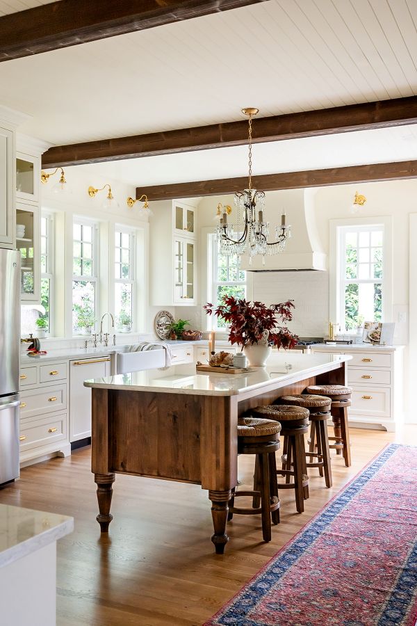 Wooden dairy table–inspired kitchen island with white quartz countertops and swivel bar stools.