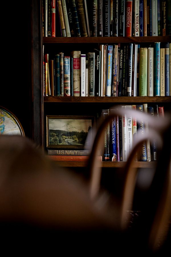 Close-up of vintage wooden desk and chair in study with custom built-in bookcases.