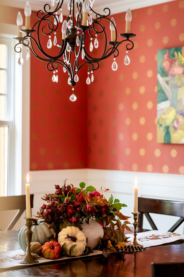 Close-up of chandelier crystals and fall centerpiece with coral hand-stamped wallpaper softly in the background.