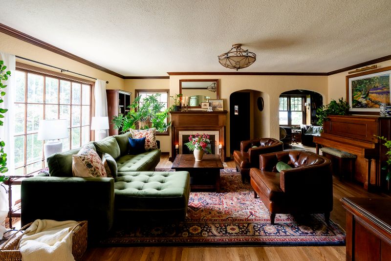 Living room with custom wood trim and moldings, featuring an arched entryway leading to the entry wall and study, and a wood fireplace mantle with detailed paneling.