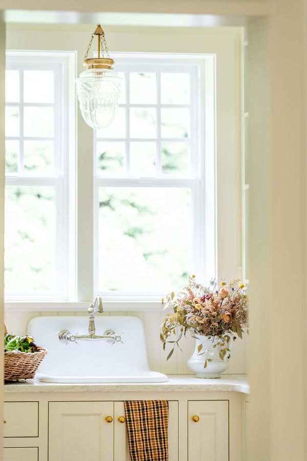 Farmhouse sink with window above offering garden view.