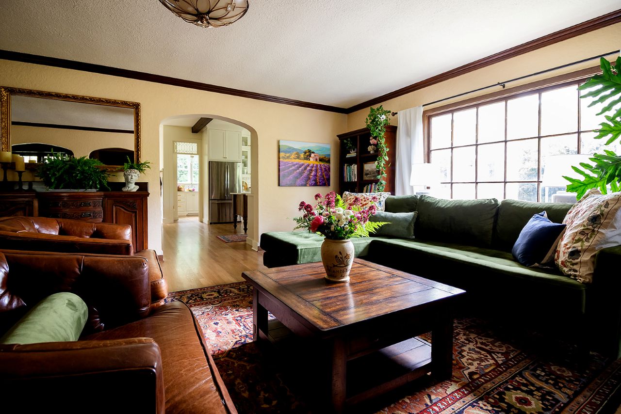 Overall view of traditional living room with wood trim, yellow walls and large window.