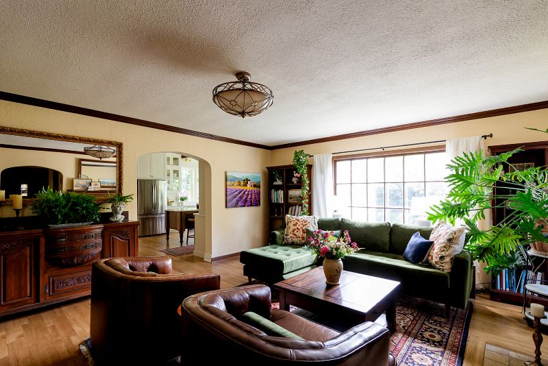 Overall view of English Cottage style living room with a view toward the kitchen through and archway.