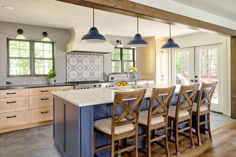 Naby blue kitchen island with barstools and 3 blue farmhouse style pendants above.