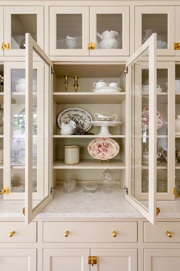Custom built-in hutch in soft greige featuring glass doors, showcasing autumn-inspired china on open shelving.