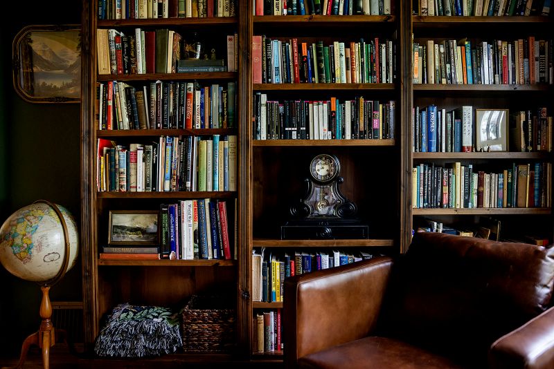 Custom built-in bookcase in study with mantle clock and rows of books.