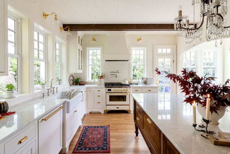 Custom wooden kitchen island featuring spacious drawers and brass handles, facing a high-end Ilve stove and handcrafted range hood.