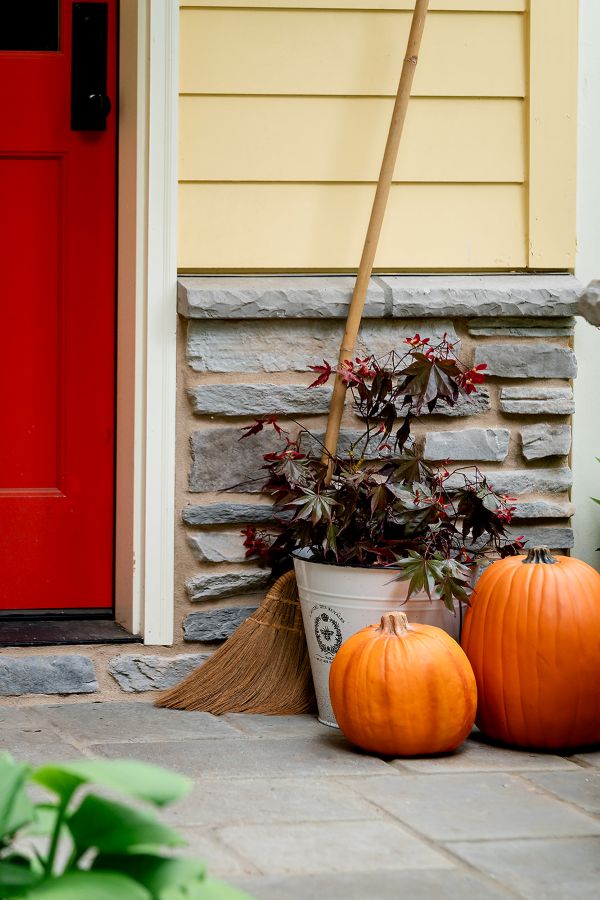 Pumpkins and broom with fall arrangement for a fall porch display.