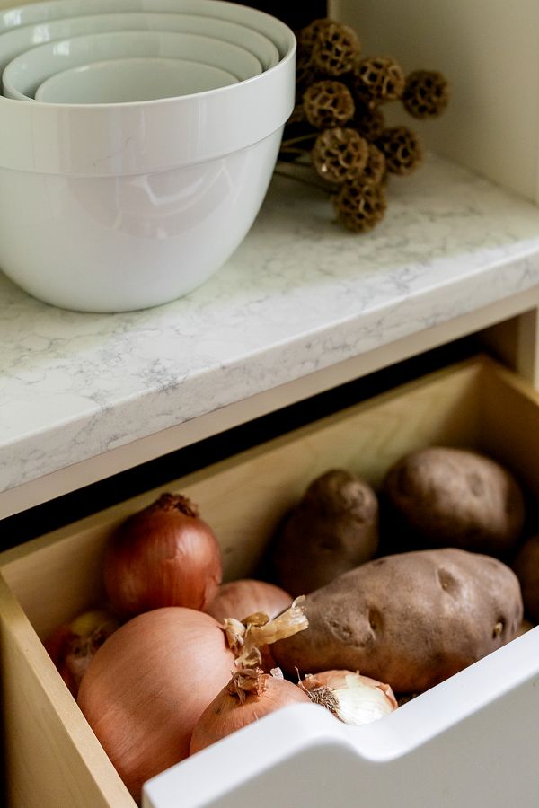 Open drawer with onions and potatoes.