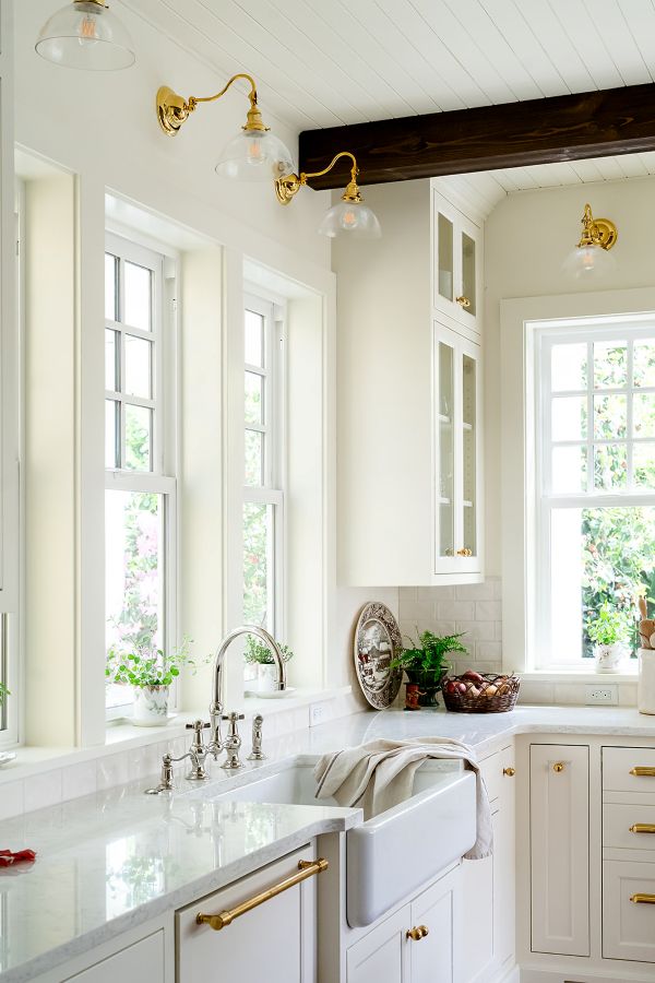 Unlacquered brass wall sconces with clear glass shades, adding warm accent lighting in the kitchen.