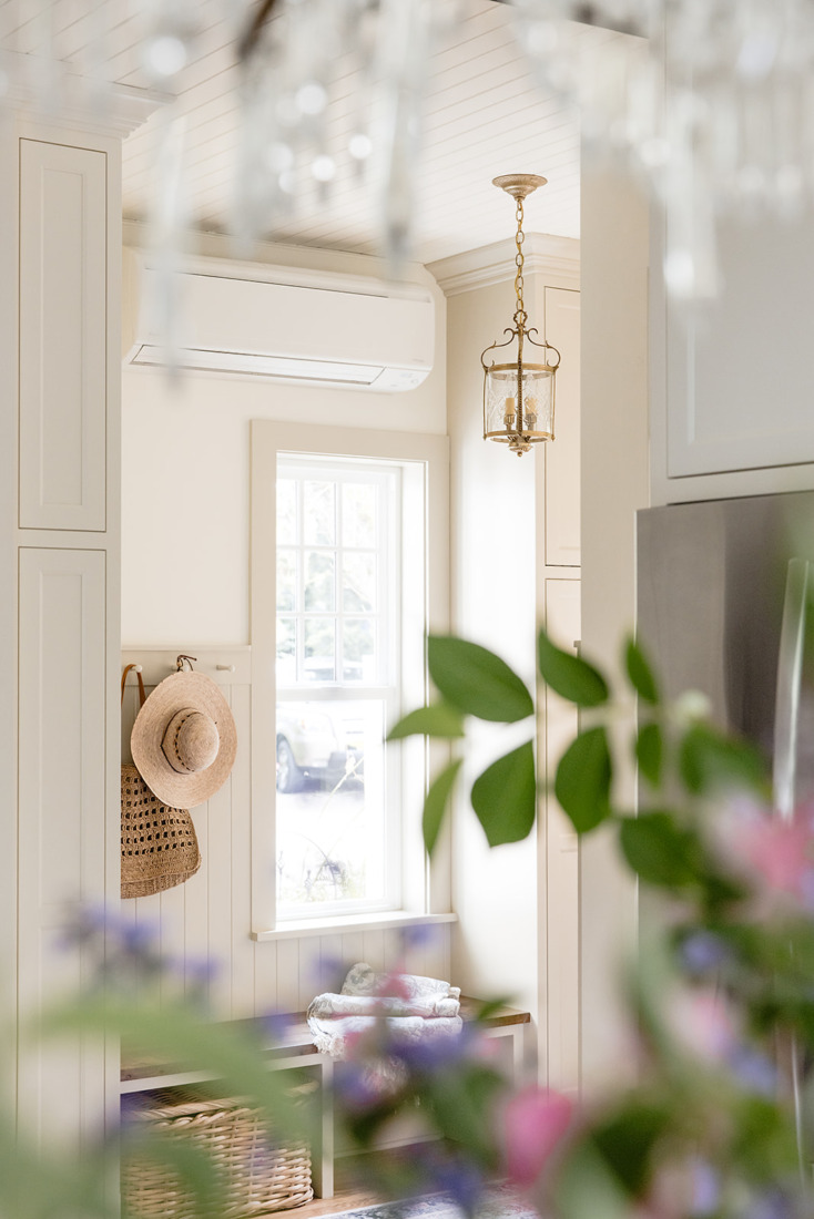 View of vestibule entry with greige wainscotting and spring florals and chandelier crystals in foreground.