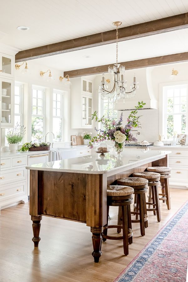 Warm wood ceiling beams, wood floors, and a wooden center island are the perfect compliment to this white kitchen