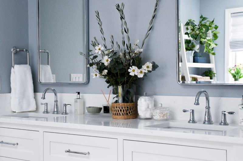 Detail shot of white quartz countertop, chrome faucets and bathroom accessories.